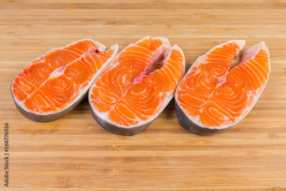 Uncooked steaks of arctic char on the wooden cutting board Uncooked steaks of arctic char on the wooden cutting board