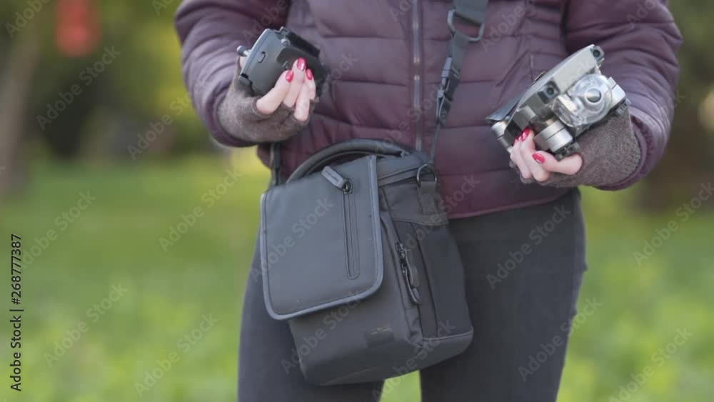 Close-up picture of a girl who is taking out a drone from the bag. She is going to take a wonderful photos of view. Close-up picture of a girl who is taking out a drone from the bag. She is going to take a wonderful photos of view.