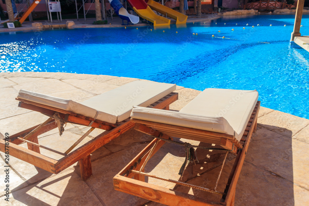 Fototapeta premium Chaise longues near a swimming pool. Concept of spa, rest, relaxation, holidays, resort