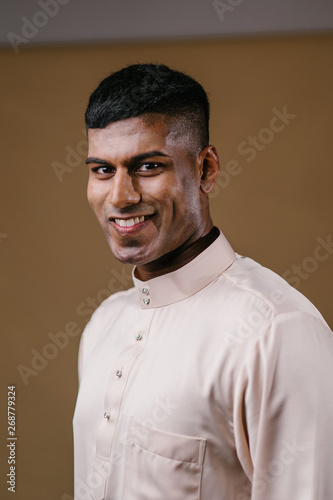 Cuadro en lienzo Portrait of a young, handsome and athletic Malaysian Indian Muslim man in a cream colored traditional baju melayu tunic