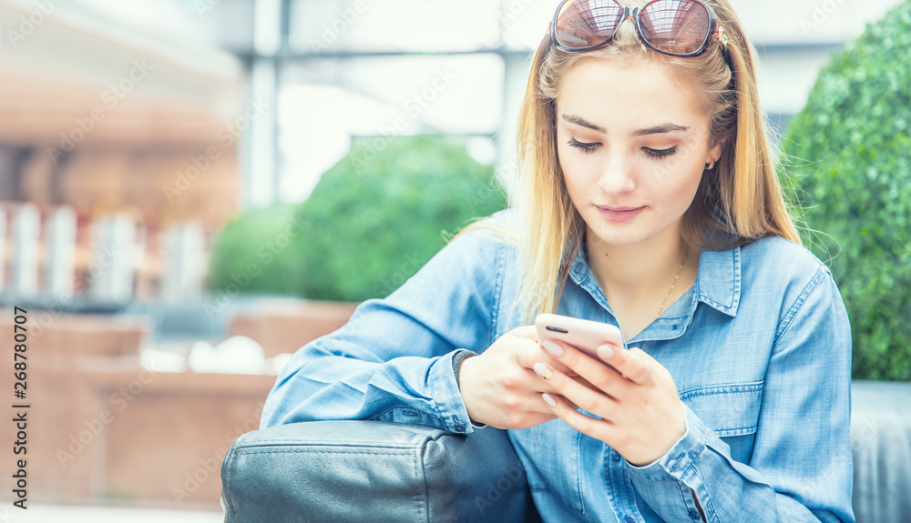 Girl texting on the smart phone in a shpping mall sitting in internet free zone Girl texting on the smart phone in a shpping mall sitting in internet free zone