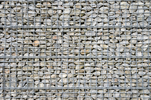 Abstract architectural background of rough retaining wall made from rocks in steel cage gabion baskets photo