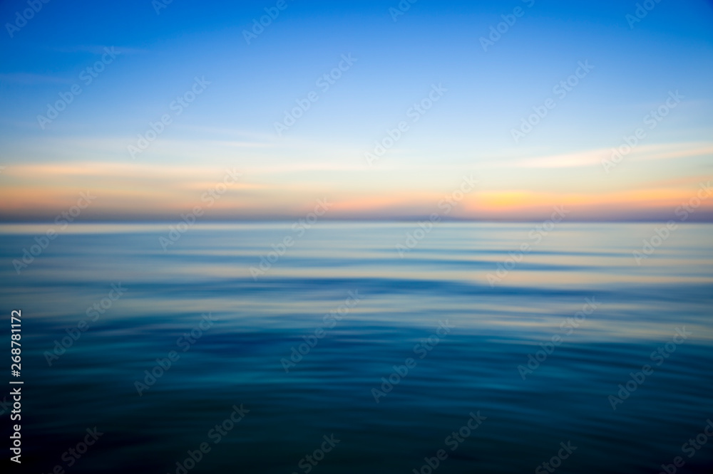 Abstract view of the glassy smooth surface waves of a calm sea during the magic hour of sunrise