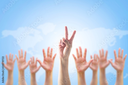 Leader's two fingers victory sign among blur hands crowd group for World participation, leadership, volunteer concept.
