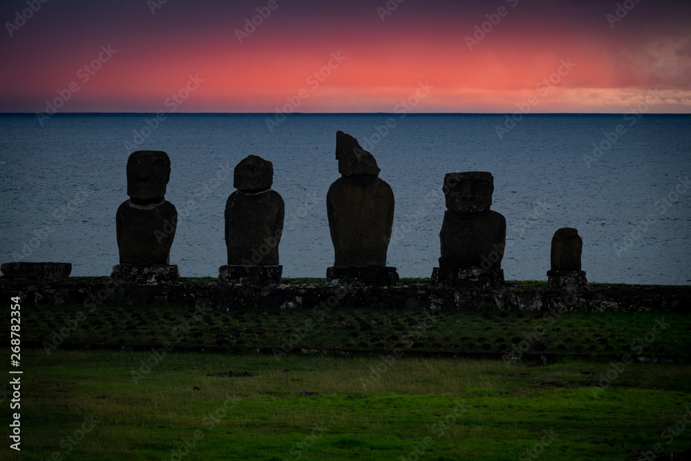 Moai shilouettes in the Ahu Tahai at sunset against pink sky