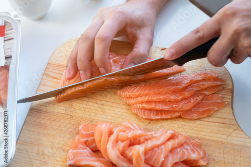 Bilde på lerret Hand cook using knife slicing a fresh salmon on chopping block