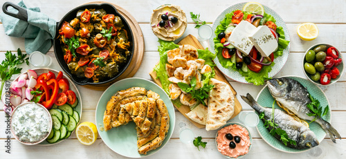 Selection of traditional greek food - salad, meze, pie, fish, tzatziki, dolma on wood background, top view photo