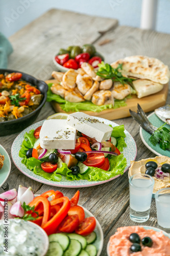 Selection of traditional greek food - salad, meze, pie, fish, tzatziki, dolma on wood background,