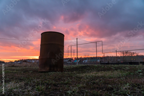old rusty barrel in the grass at sunset