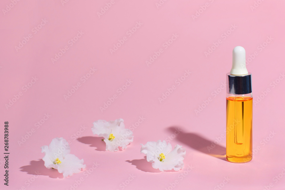 Dropper glass Bottle Mock-Up. Serum skin care cosmetics and white delicate flower on pink background, banner or template. Beauty product concept. Dropper glass Bottle Mock-Up. Serum skin care cosmetics and white delicate flower on pink background, banner or template. Beauty product concept.