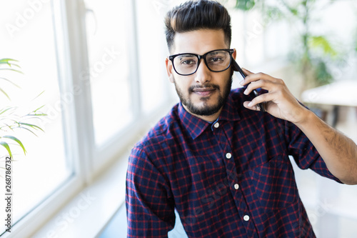 Young indian business man talking on the phone in modern office