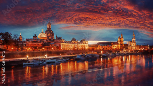Fantastic colorful sunset in Dresden with dramatic sky, over the Elbe river. Old Town glowing in lighten reflected in calm water. Picturesque unusual scene. Creative image