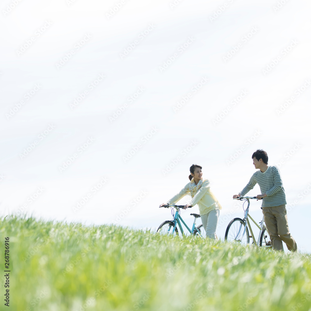 Obraz premium 草原で自転車を押すカップル