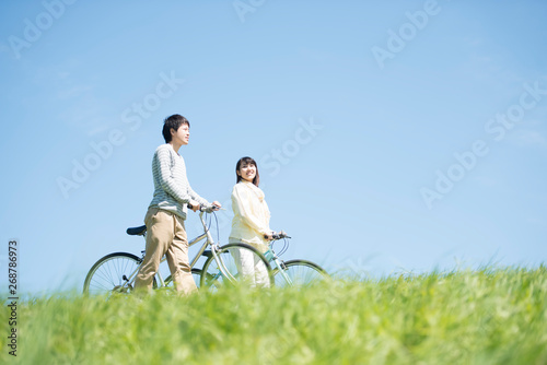 草原で自転車を押すカップル