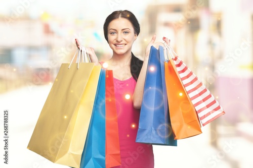 Young woman with shopping bags on background