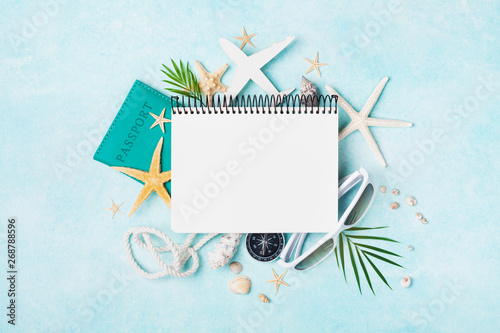Open notebook with accessories on blue pastel table top view. Planning summer holidays, travel and vacation background. Flat lay style. photo