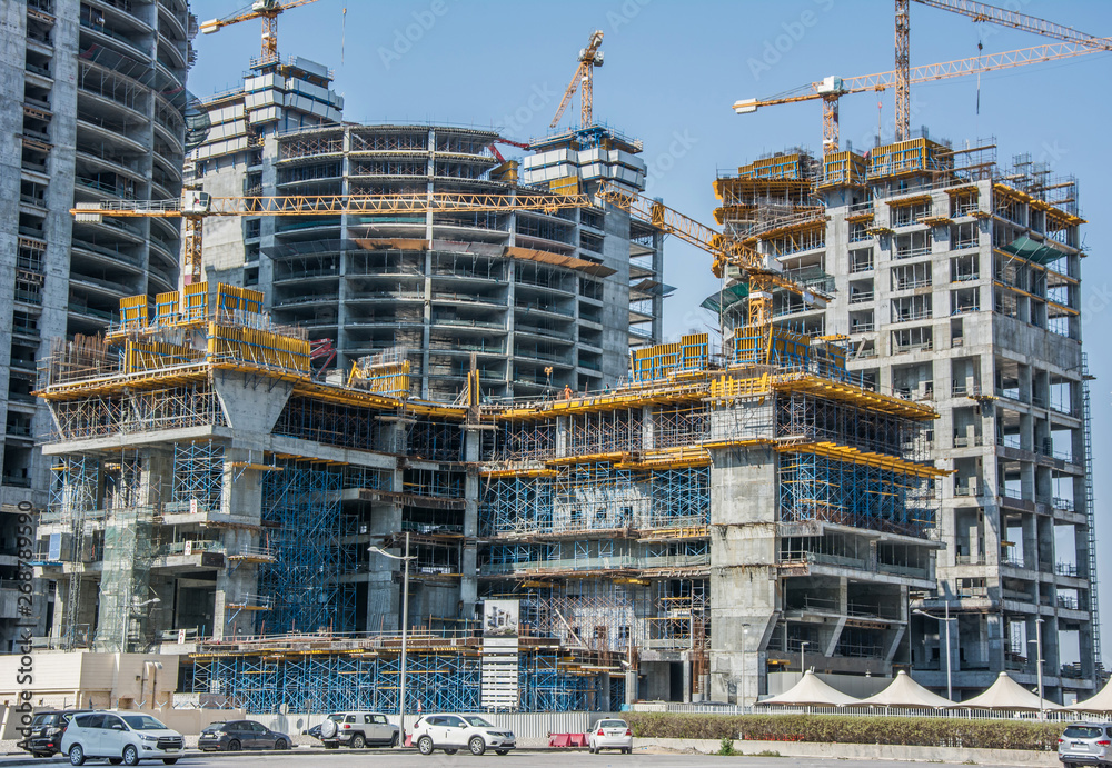 High-rise buildings with yellow cranes and scaffolding at construction site