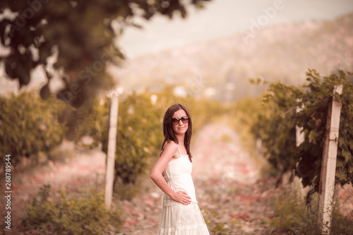 Smiling woman in white dress standing in vineyard