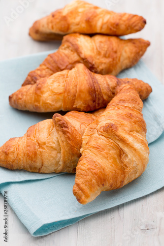 Tasty buttery croissants on old wooden table.