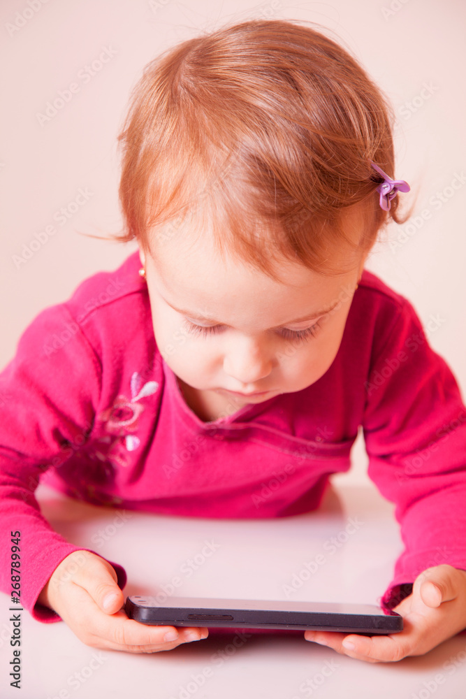 Social Media addiction. Little child girl holding smart phone (psychological problems, media mania, education concept) Social Media addiction. Little child girl holding smart phone (psychological problems, media mania, education concept)