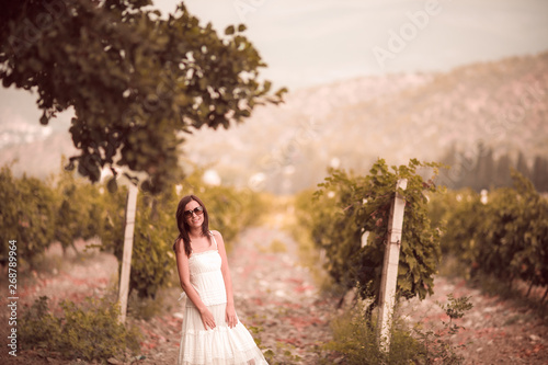 Smiling woman in white dress standing in vineyard