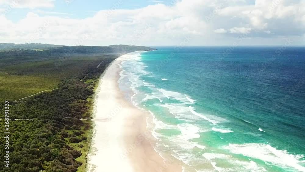 Drone flying along a white sand beach splitting through a jungle and turquoise blue ocean water Drone flying along a white sand beach splitting through a jungle and turquoise blue ocean water