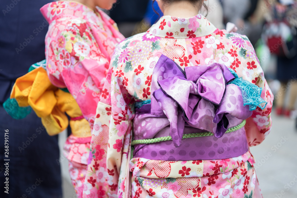 Naklejka premium Young girl wearing Japanese kimono standing in front of Sensoji Temple in Tokyo, Japan. Kimono is a Japanese traditional garment. The word 