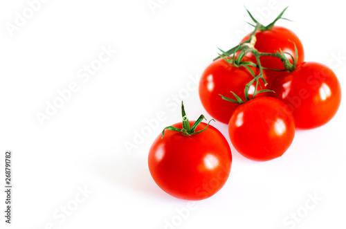 Red juicy cherry tomatoes with green tails lying on a white background