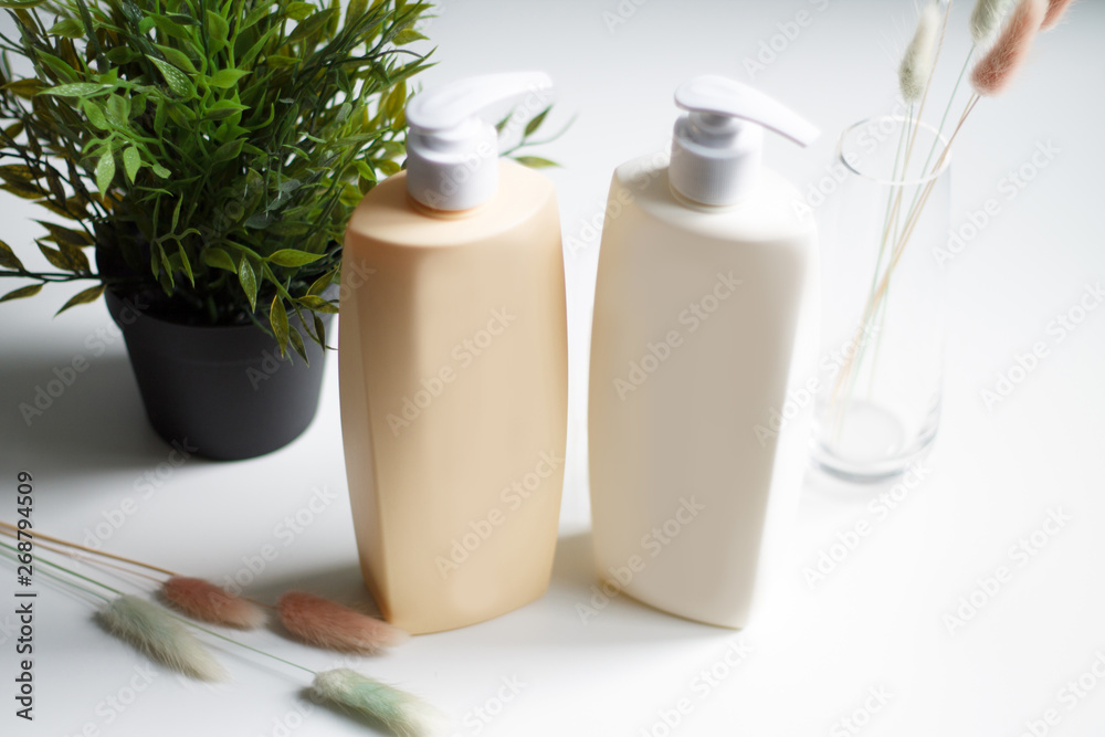 shampoo bottles cream beige and white blank for writing pattern on light green flower background .