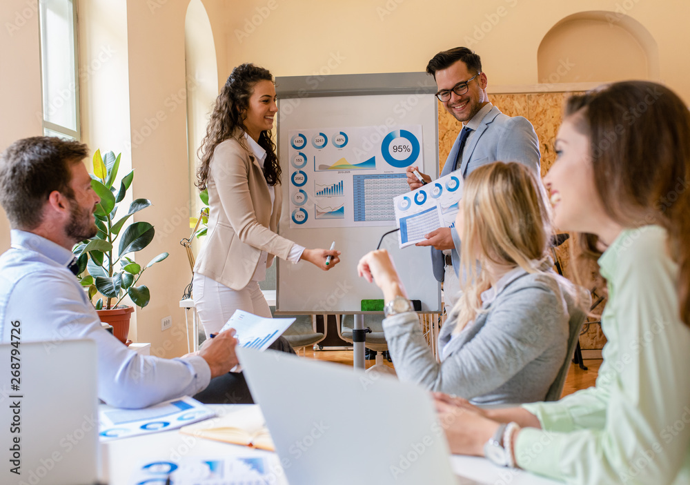 Group of young business people working together in office, two coworker conducting a business presentation using flip chart. Group of young business people working together in office, two coworker conducting a business presentation using flip chart.
