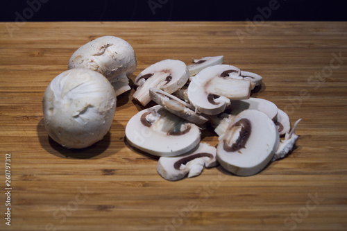 Mushrooms freshly cut into slices with a knife and placed on a wooden board prepared for cooking in the kitchen.
