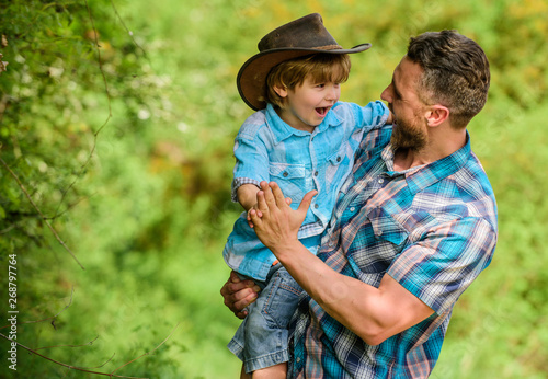 Power being father. Rustic family. Growing cute cowboy. Small helper in garden. Little boy and father in nature background. Spirit of adventures. Strong like father. Child having fun cowboy dad © be free