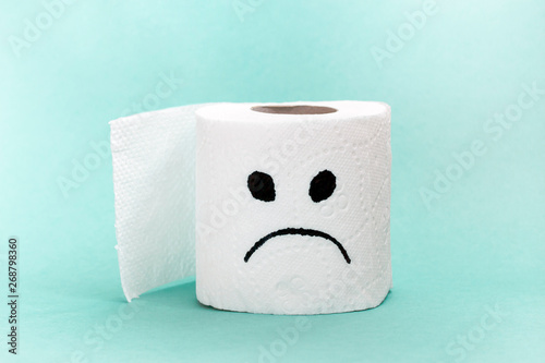 White toilet paper with sad face. Creative concept constipation, indigestion, digestion problem. photo