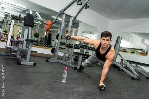 Athletic man in gym working with dumbbells