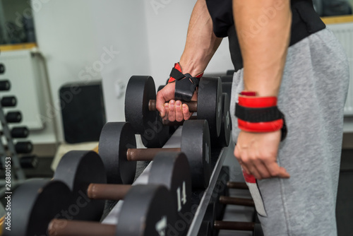 Athletic man in gym working with dumbbells