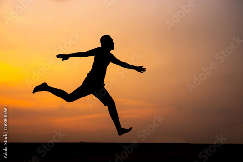 Wallpaper Mural Man running alone at beautiful sunset in the road at park . Summer sport and freedom concept. Athlete training on dusk. - Image Torontodigital.ca