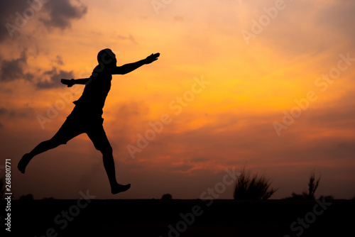 Man running alone at beautiful sunset in the road at park . Summer sport and freedom concept. Athlete training on dusk. - Image