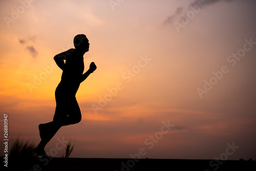 Man running alone at beautiful sunset in the road at park . Summer sport and freedom concept. Athlete training on dusk. - Image