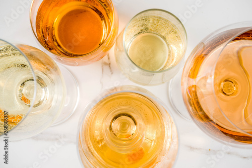 Fotografía Trendy orange wine, with white wine in different glasses, white concrete backgro