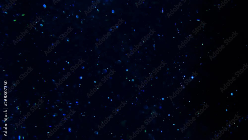 Blue glitter in blur on a black background.