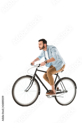 handsome bearded man riding bicycle and looking ahead isolated on white