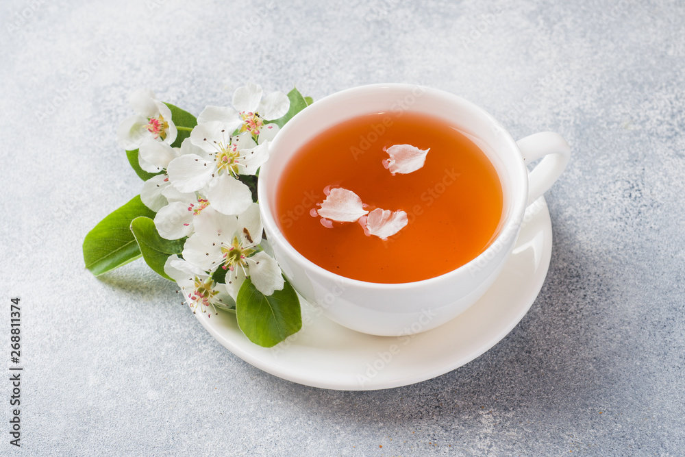 Cup of tea and blooming Apple branch on a gray concrete background with copy space. Concept morning Breakfast. Cup of tea and blooming Apple branch on a gray concrete background with copy space. Concept morning Breakfast.
