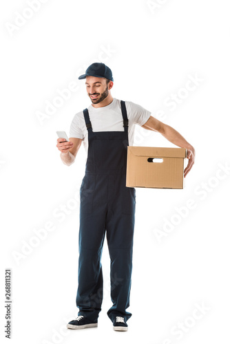 smiling delivery man using smartphone while holding cardboard box isolated on white © LIGHTFIELD STUDIOS