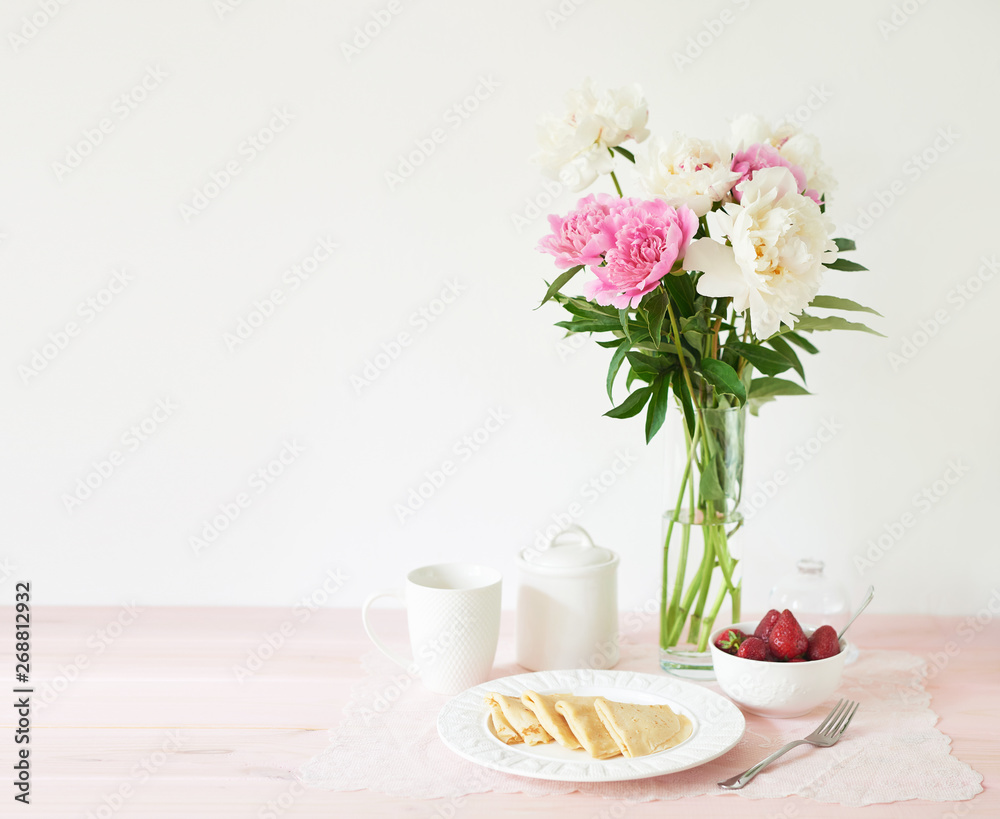 pancakes with strawberries and coffee on the table near a vase with peonies on a white background pancakes with strawberries and coffee on the table near a vase with peonies on a white background