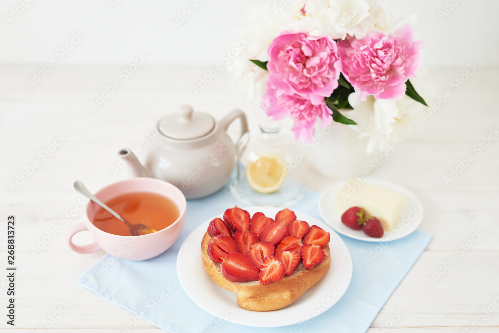 strawberry with croissant and tea on the table near a vase with peonies on a white background strawberry with croissant and tea on the table near a vase with peonies on a white background