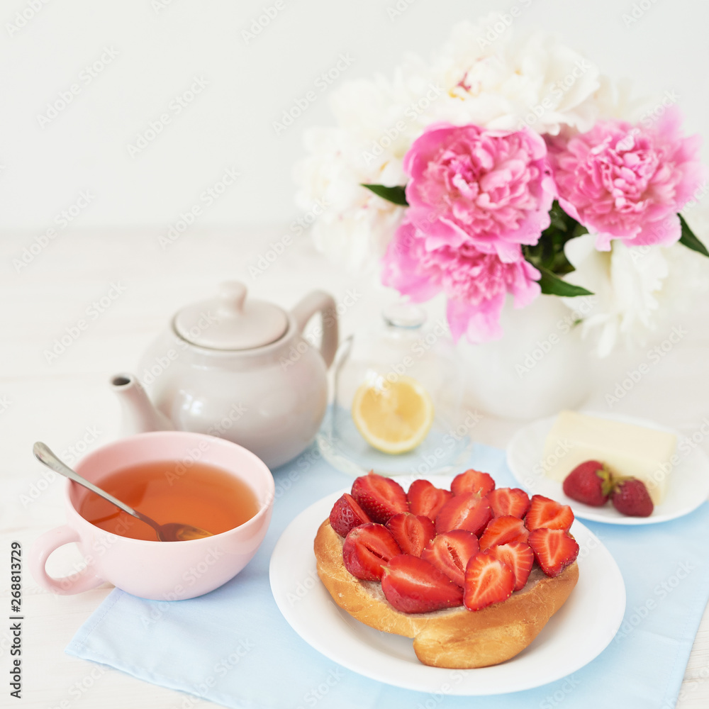 strawberry with croissant and tea on the table near a vase with peonies on a white background strawberry with croissant and tea on the table near a vase with peonies on a white background