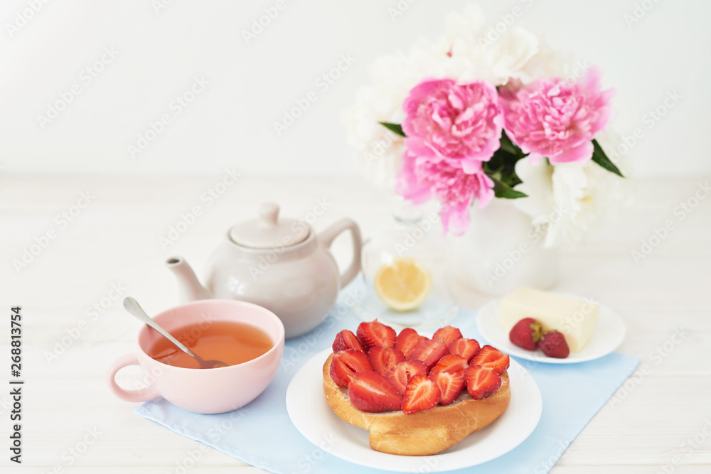 strawberry with croissant and tea on the table near a vase with peonies on a white background strawberry with croissant and tea on the table near a vase with peonies on a white background