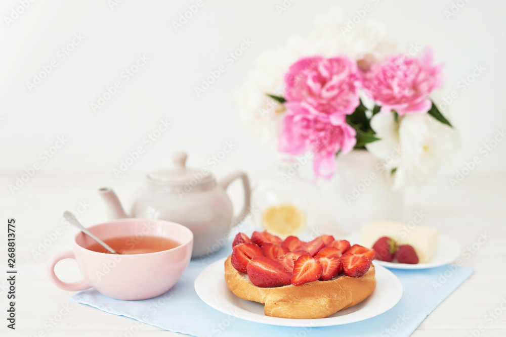 strawberry with croissant and tea on the table near a vase with peonies on a white background strawberry with croissant and tea on the table near a vase with peonies on a white background