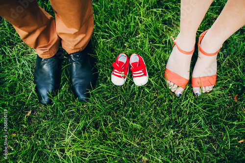 waiting for a miracle. shoes for adults and children. children's shoes on the grass between the legs of the parents.