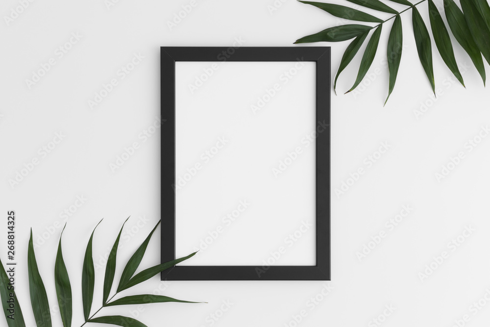 Top view of a black frame mockup with palm leaf decoration. Portrait orientation. Top view of a black frame mockup with palm leaf decoration. Portrait orientation.